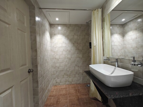 Une salle de bain avec une baignoire, une douche, des murs carrelés et une porte.