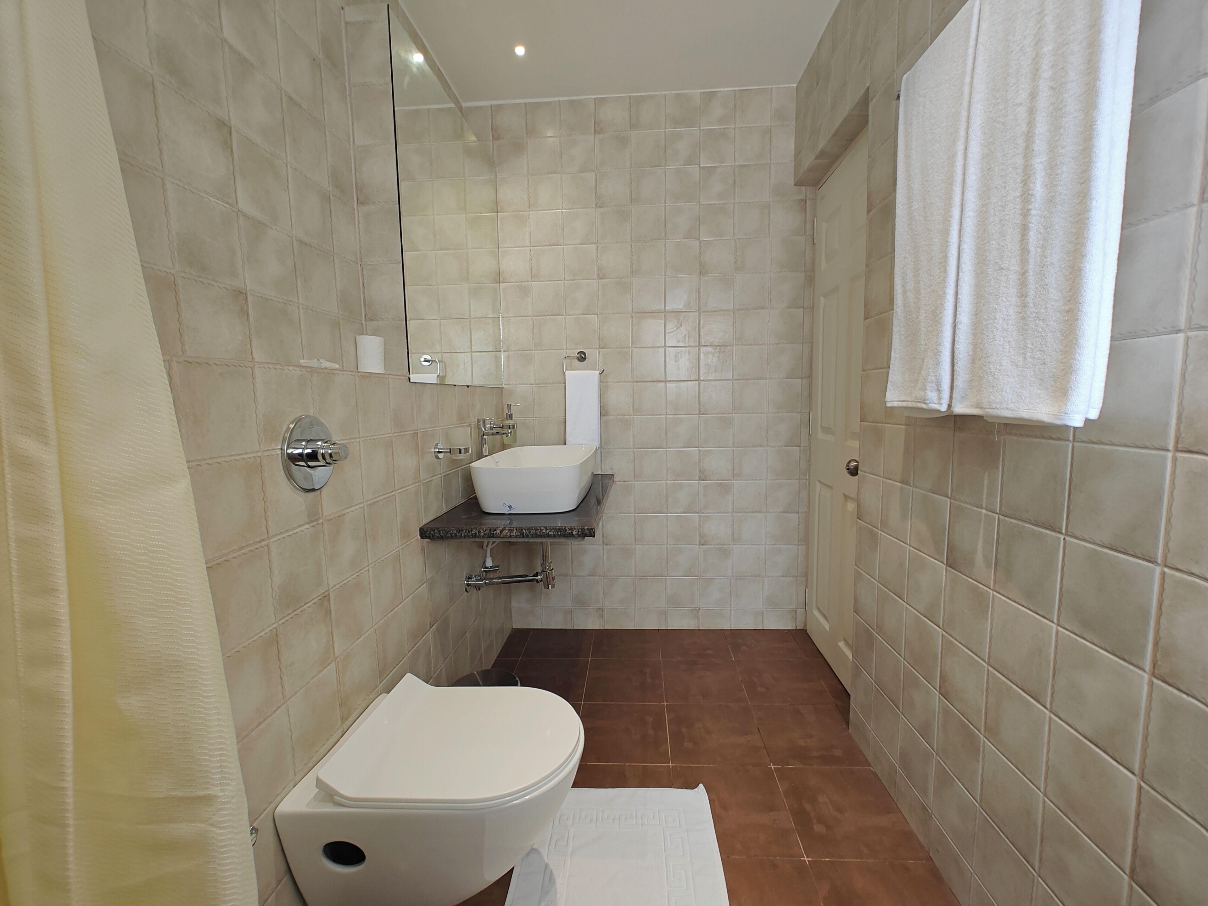 A bathroom with a toilet, sink, and mirror.