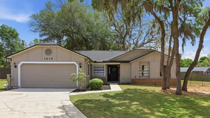 A single-story house with a garage, a front door, and a mailbox. - Cozy Orlando getaway | Near Disney | Fenced Yard (Ocoee)