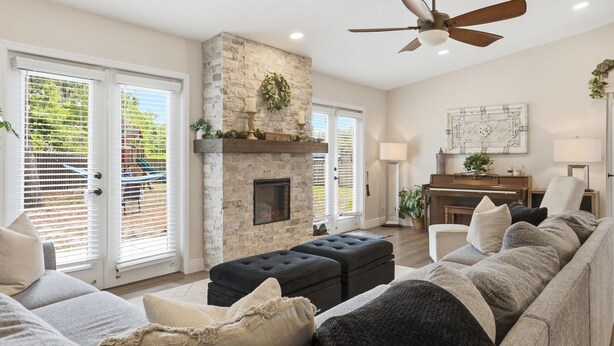 A living room with a stone fireplace, a ceiling fan, and a piano. - Cozy Orlando getaway | Near Disney | Fenced Yard (Ocoee)