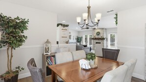 A dining area with a wooden table, chairs, a chandelier, and a potted plant. - Cozy Orlando getaway | Near Disney | Fenced Yard (Ocoee)