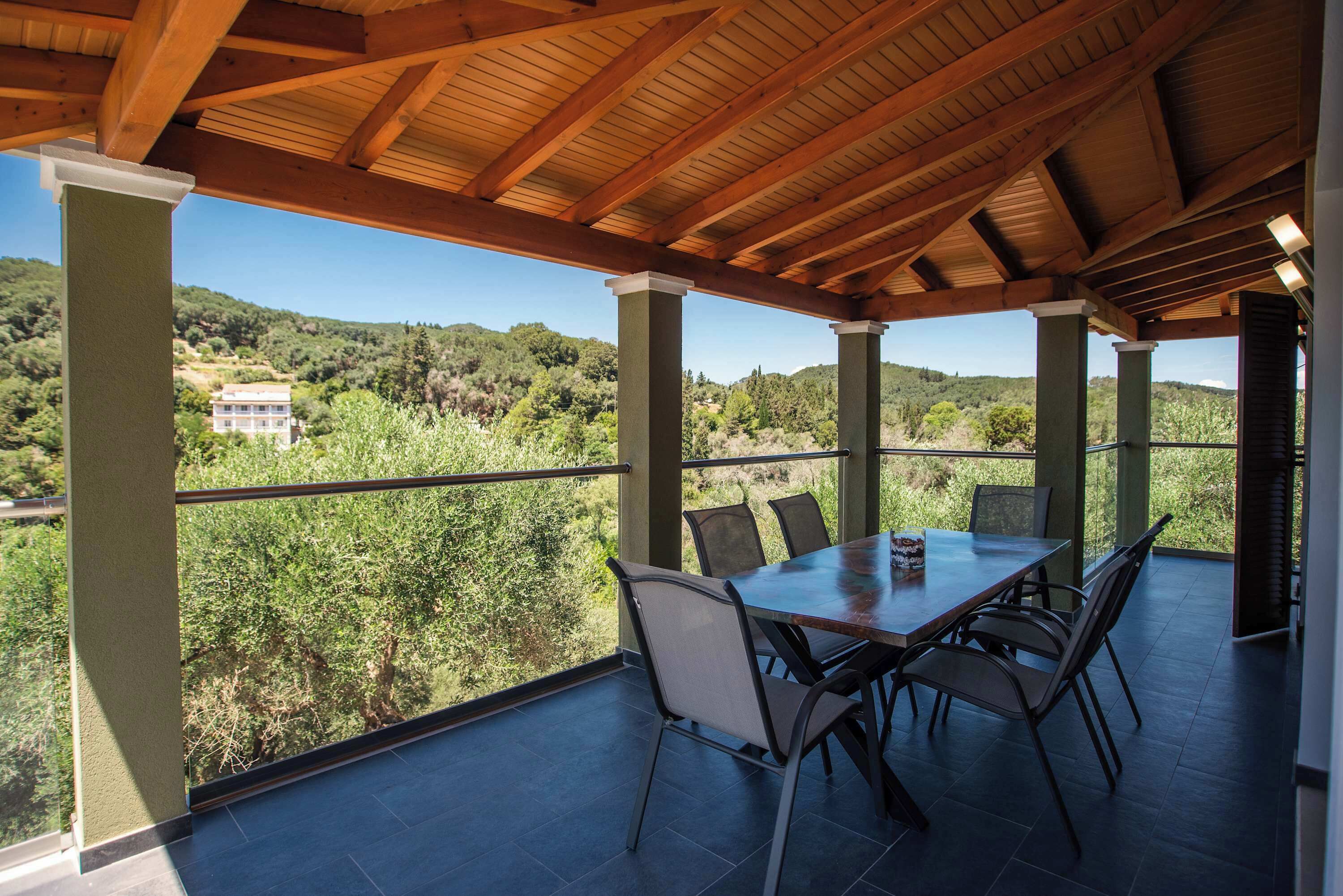 Un espacio de comedor al aire libre techado con vista a una colina.