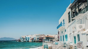 A seaside terrace with white buildings, blue accents, and outdoor seating by the water. - Eidolion Essence Mykonos Villa w Private Pool up to 10 ppl (Mykonos)