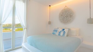 A bedroom with a bed, a wall-mounted light, and a view through a glass door. - Eidolion Essence Mykonos Villa w Private Pool up to 10 ppl (Mykonos)