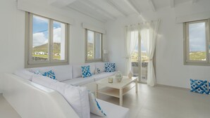A modern living room with a white sofa, a coffee table, and large windows with curtains. - Eidolion Essence Mykonos Villa w Private Pool up to 10 ppl (Mykonos)