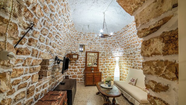 A stone-walled room with a sofa, a wooden table, a TV, and a mirror. - Villino Salentum With Private Pool and Garden (Racale)