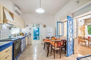 A compact kitchen with a stove, sink, and dining area with chairs and a table. - Villino Salentum With Private Pool and Garden (Racale)