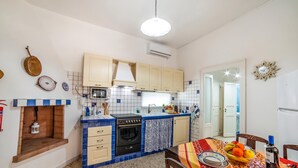 A compact kitchen with a stove, oven, and sink, a dining area with a table set for two, and a small window. - Villino Salentum With Private Pool and Garden (Racale)