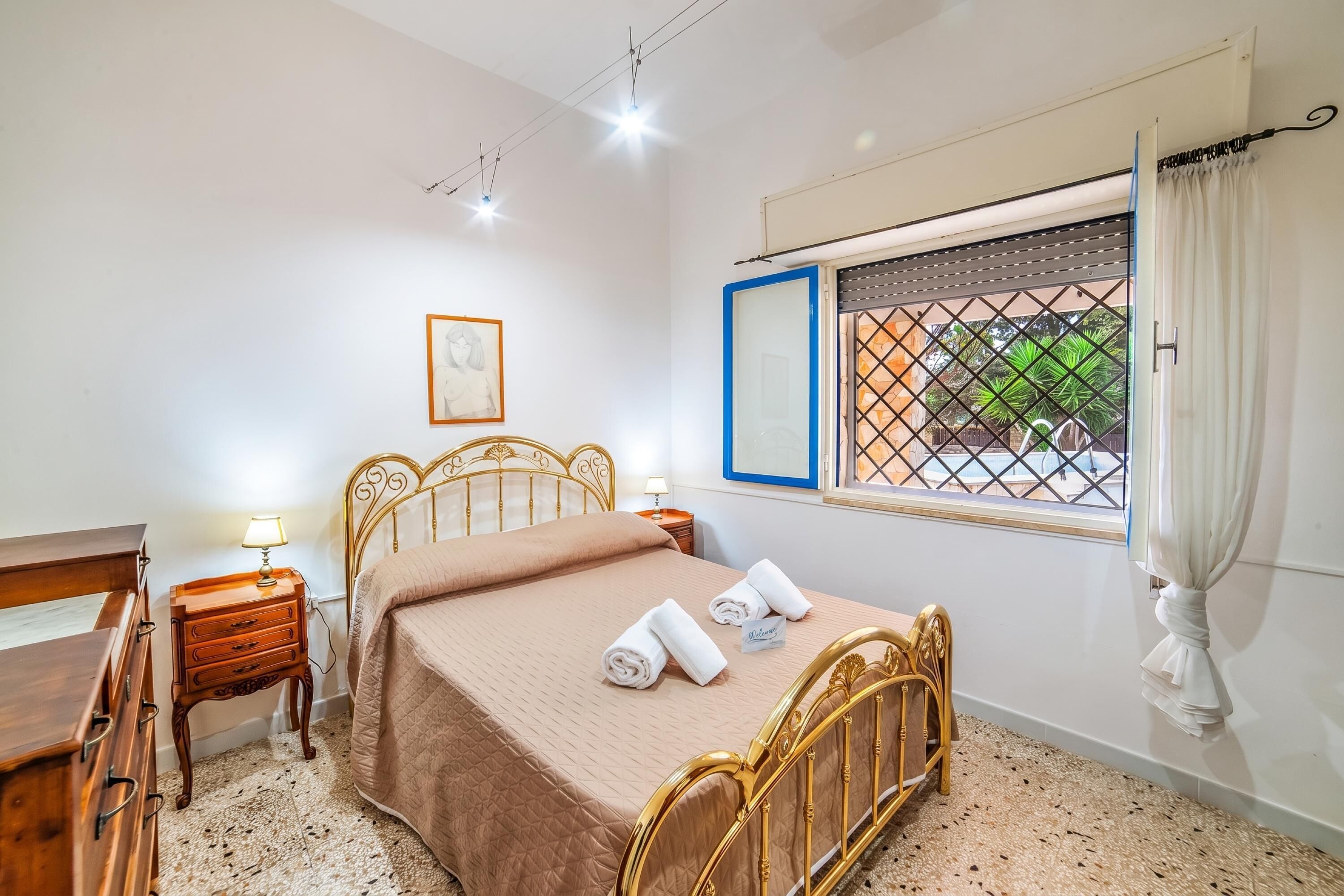 Una camera da letto con un letto, comodini, una scrivania, una finestra vista e un quadro appeso al muro.