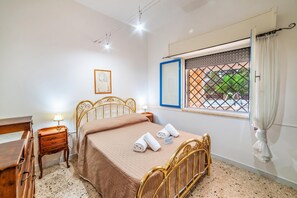 Una camera da letto con un letto, comodini, una scrivania, una finestra vista e un quadro appeso al muro.