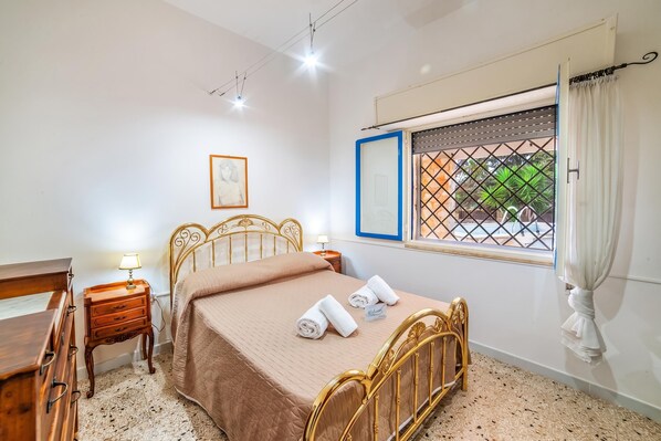 Une chambre à coucher comprenant un lit, des tables de chevet, un bureau, une fenêtre avec vue et un tableau encadré au mur.
