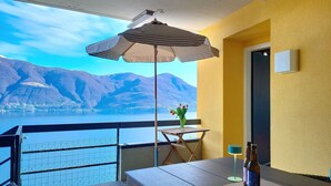 Ein Balkon mit Tisch, Stühlen, Sonnenschirm und einer Flasche.