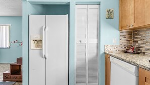 Una cocina con un refrigerador blanco, un lavavajillas blanco y armarios de madera.