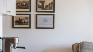Una habitación con cafetera, una silla y cuatro cuadros en la pared.