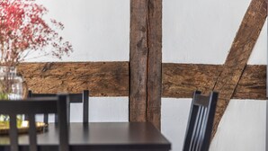 Una mesa de comedor con sillas, una viga de madera y una pared blanca.