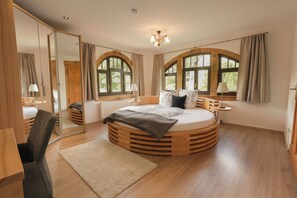 A circular bed with a wooden frame, a large mirror, and two windows with curtains. - Modern Art Nouveau villa in the natural paradise of Großer Gleichberg (Römhild)