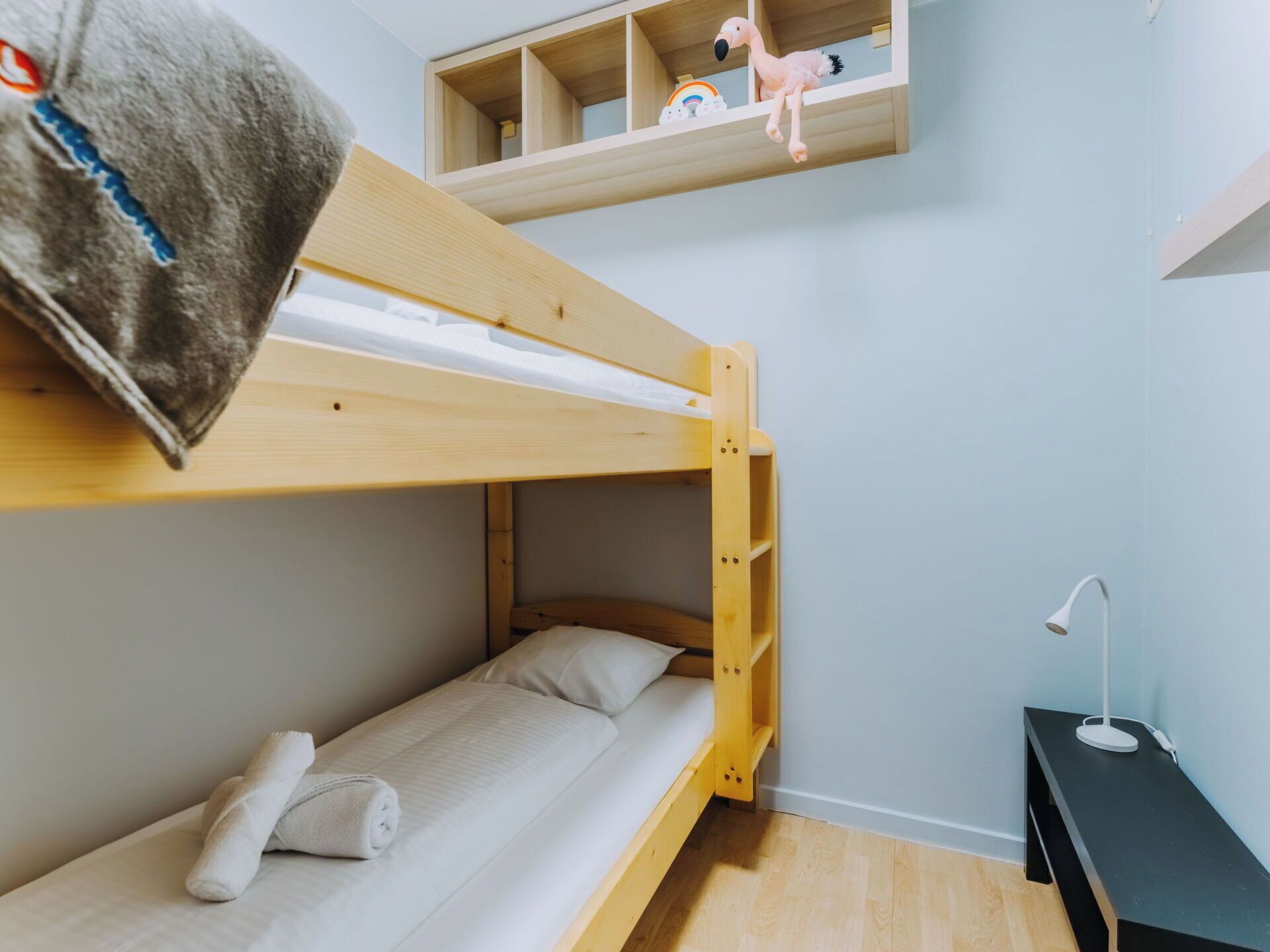 Une chambre avec un lit superposé, un bureau et une étagère au-dessus.