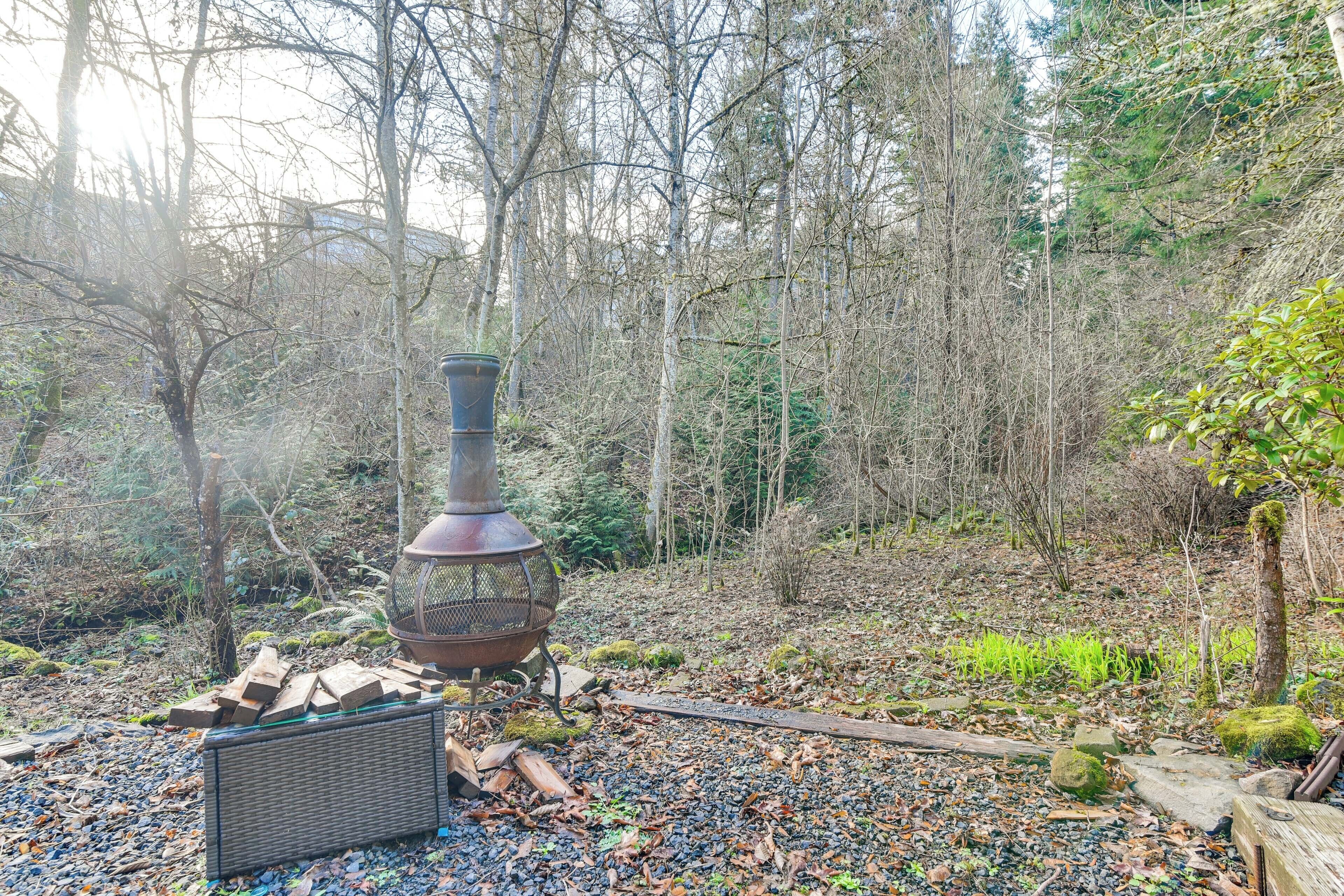 A rustic outdoor setting with a wood-burning stove, logs, and a wicker basket.