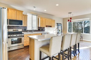 A modern kitchen with wooden cabinets, stainless steel appliances, and a large island with bar stools.