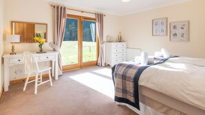 A bedroom with a bed, a desk, a chair, a dresser, a radiator, and a window with curtains. - Stunning private villa for 8 people with WIFI, TV, terrace and panoramic view (Invermoriston)