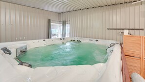 Ein Whirlpool mit Blick ins Freie, eine hölzerne Bank und ein Metallgeländer.
