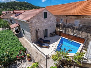 Ein Steinhaus mit rotem Ziegeldach, einem Schwimmbecken und einer Sitzgelegenheit im Freien.