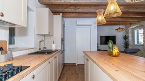 Eine moderne Küche mit Holzarbeitsplatten, weißen Schränken, einem eingebauten Herd und einer Holzbalkendecke.