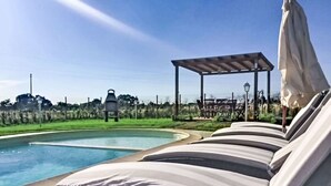 Ein Poolbereich mit Liegestühlen und einer Pergola.