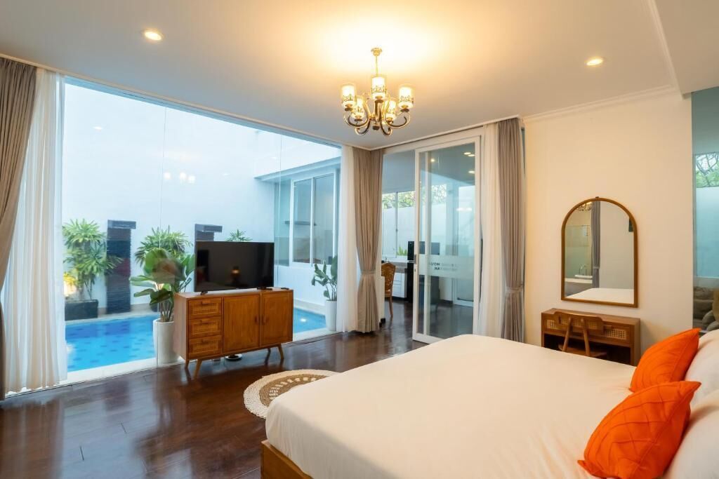 Ein Hotelzimmer mit einem großen Bett, einem Fernseher, einer Holzkombination und Blick auf einen Pool.