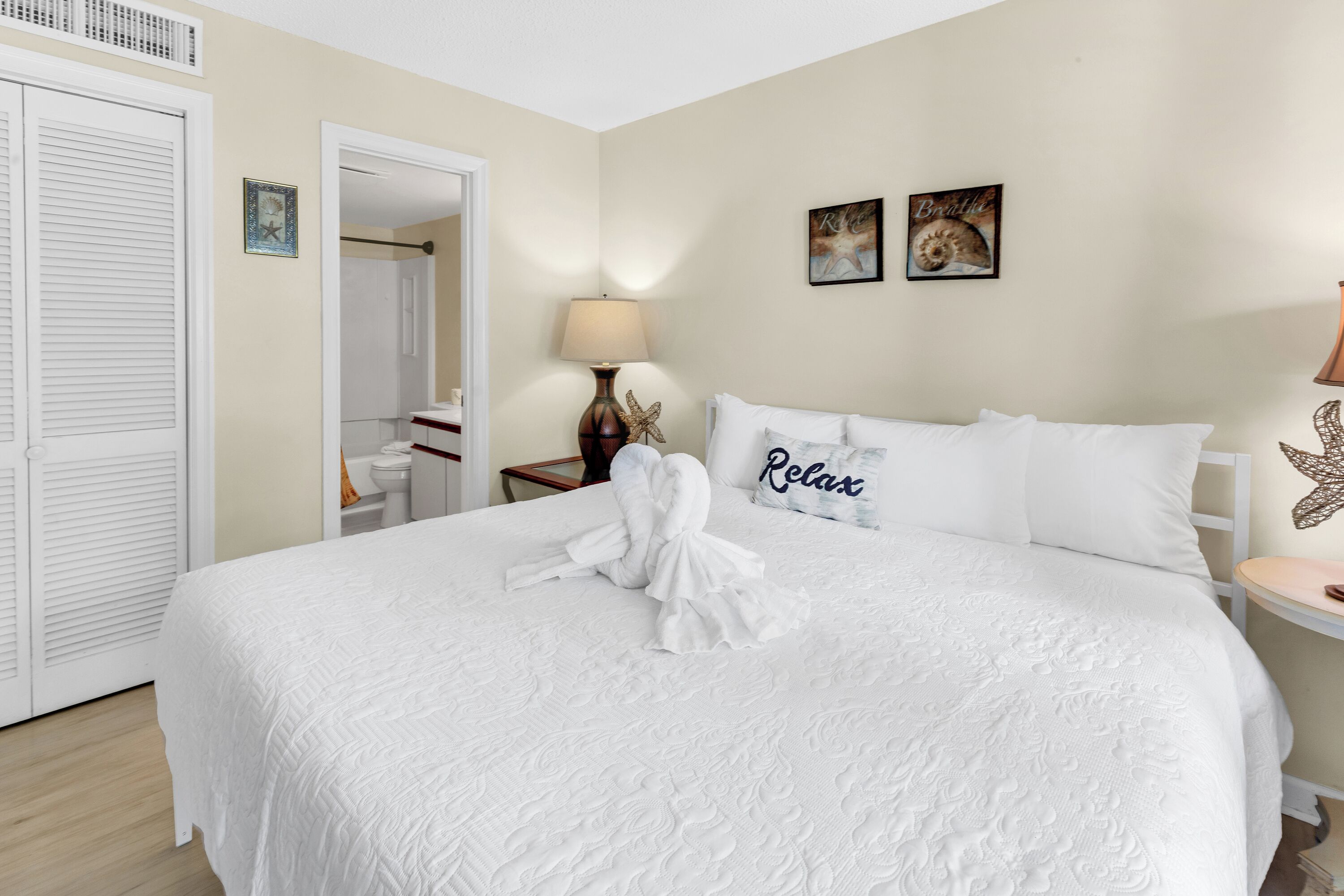 A neatly made bed with a white comforter and pillows, a bedside lamp, and a starfish decoration on the nightstand.