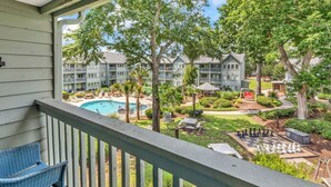 A balcony with a view of a swimming pool, outdoor chess set, and a well-maintained garden. - Myrtle Beach Resort 6306 (Myrtle Beach)