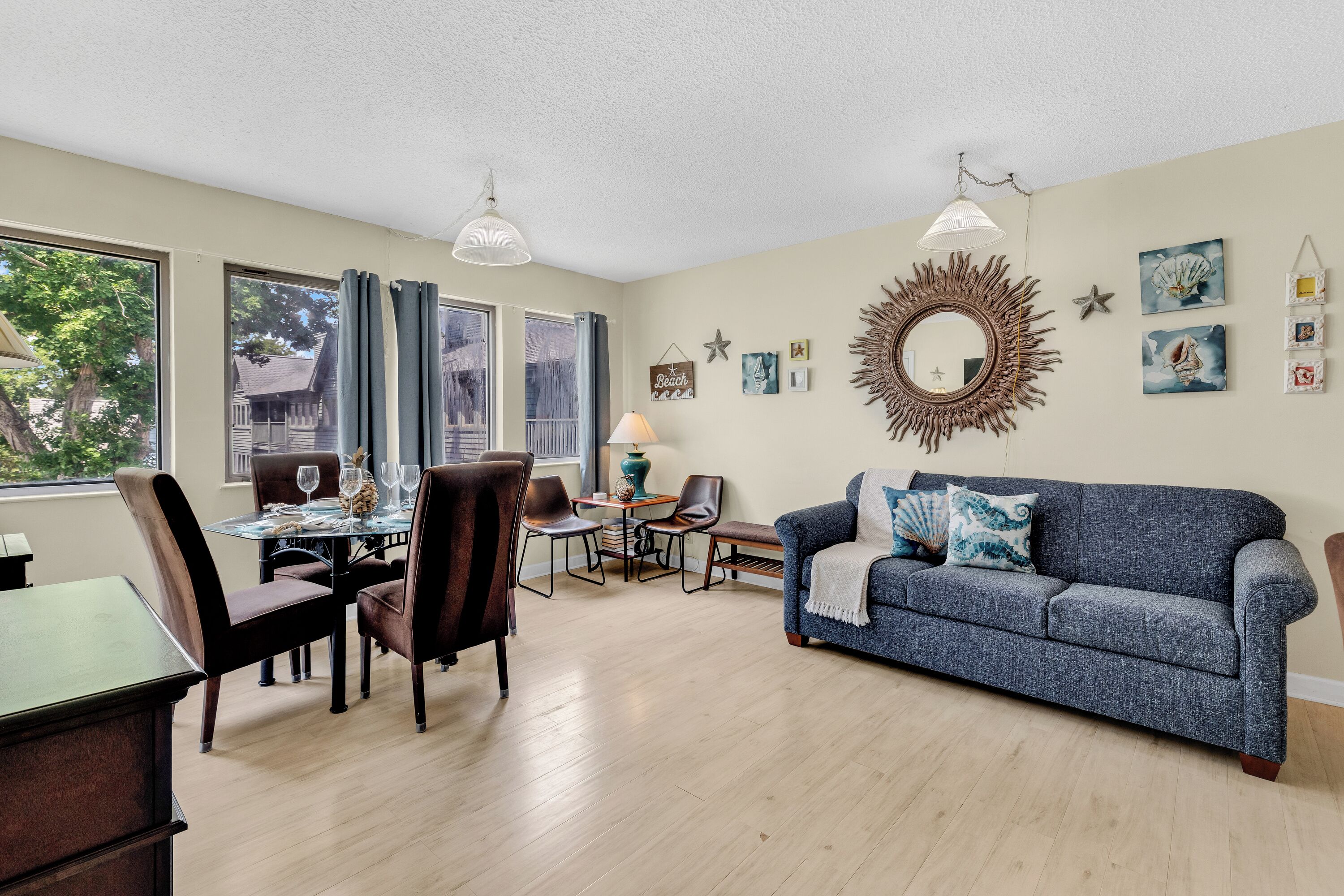 A living room with a dining table, chairs, a sofa, and a lamp.