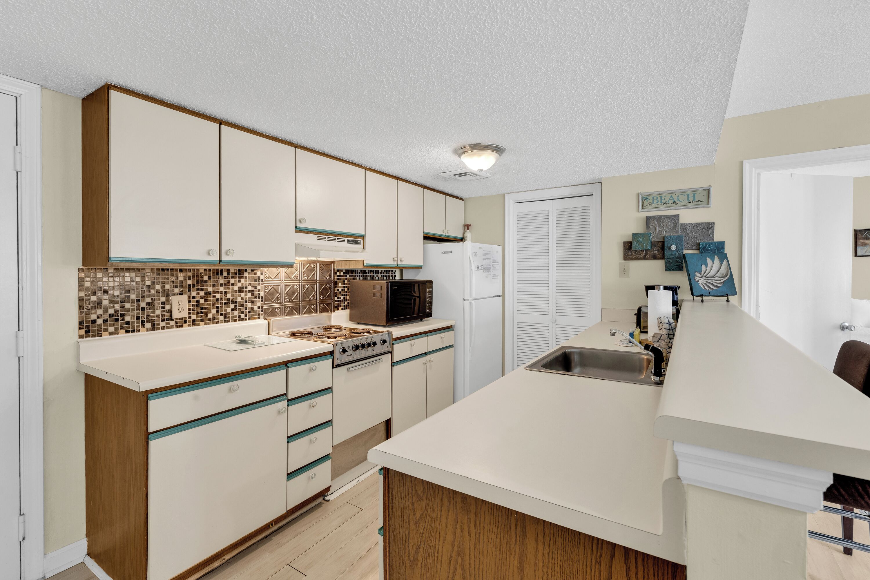 A kitchen with white cabinets, a microwave, a refrigerator, and a tiled backsplash.