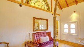 Una habitación con un ventanal grande, un espejo y un sofá rosa.