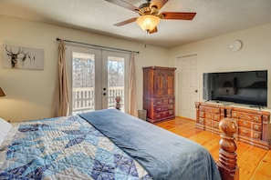 A bedroom with a bed, a ceiling fan, a wooden dresser, a television, and a door leading to a balcony. - 2 Mi to Dtwn Ellijay! Outdoorsy Escape w/ Hot Tub (Ellijay)