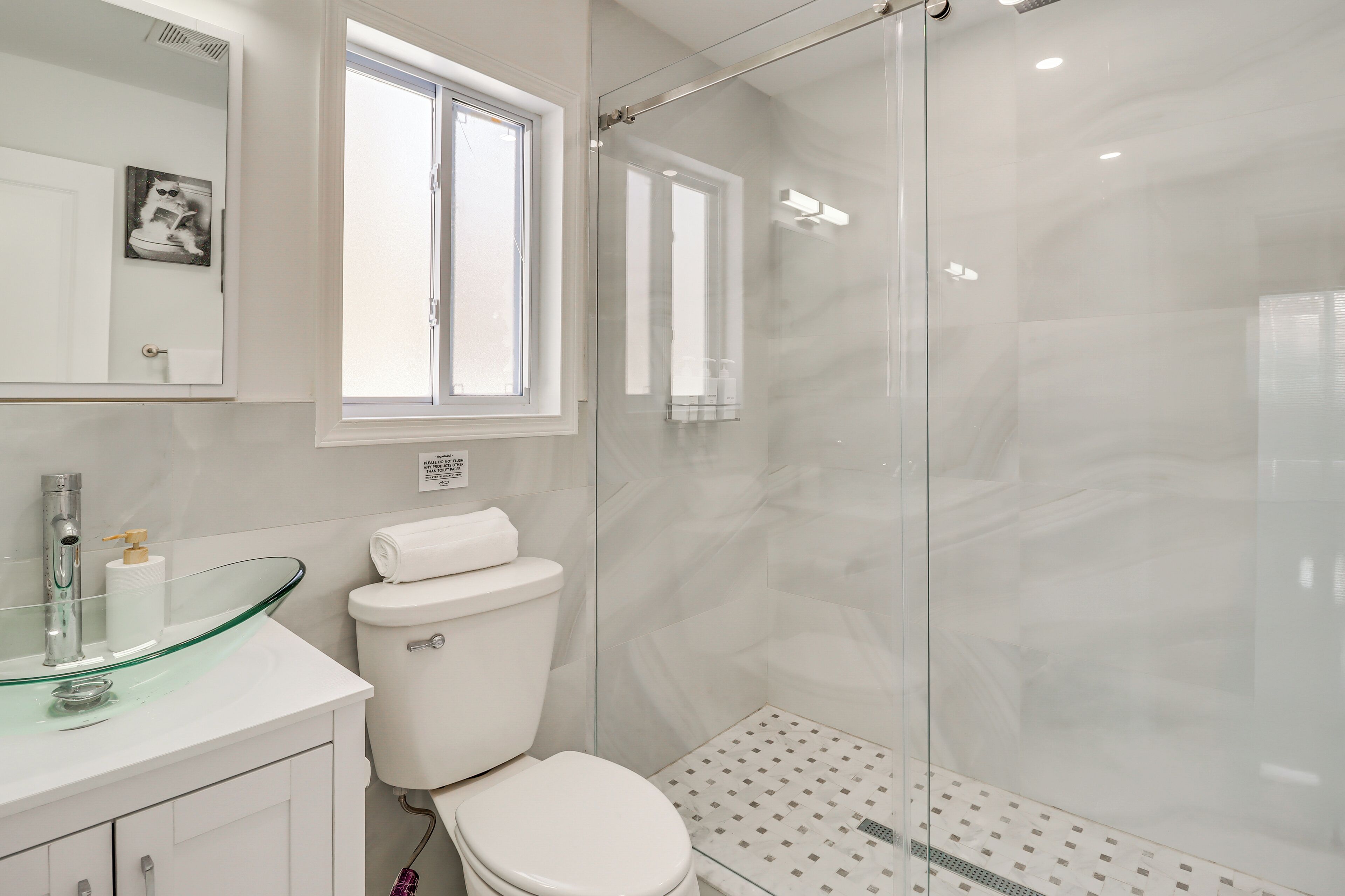 Une salle de bain moderne avec une douche à parois de verre, des toilettes blanches et un lavabo en verre.