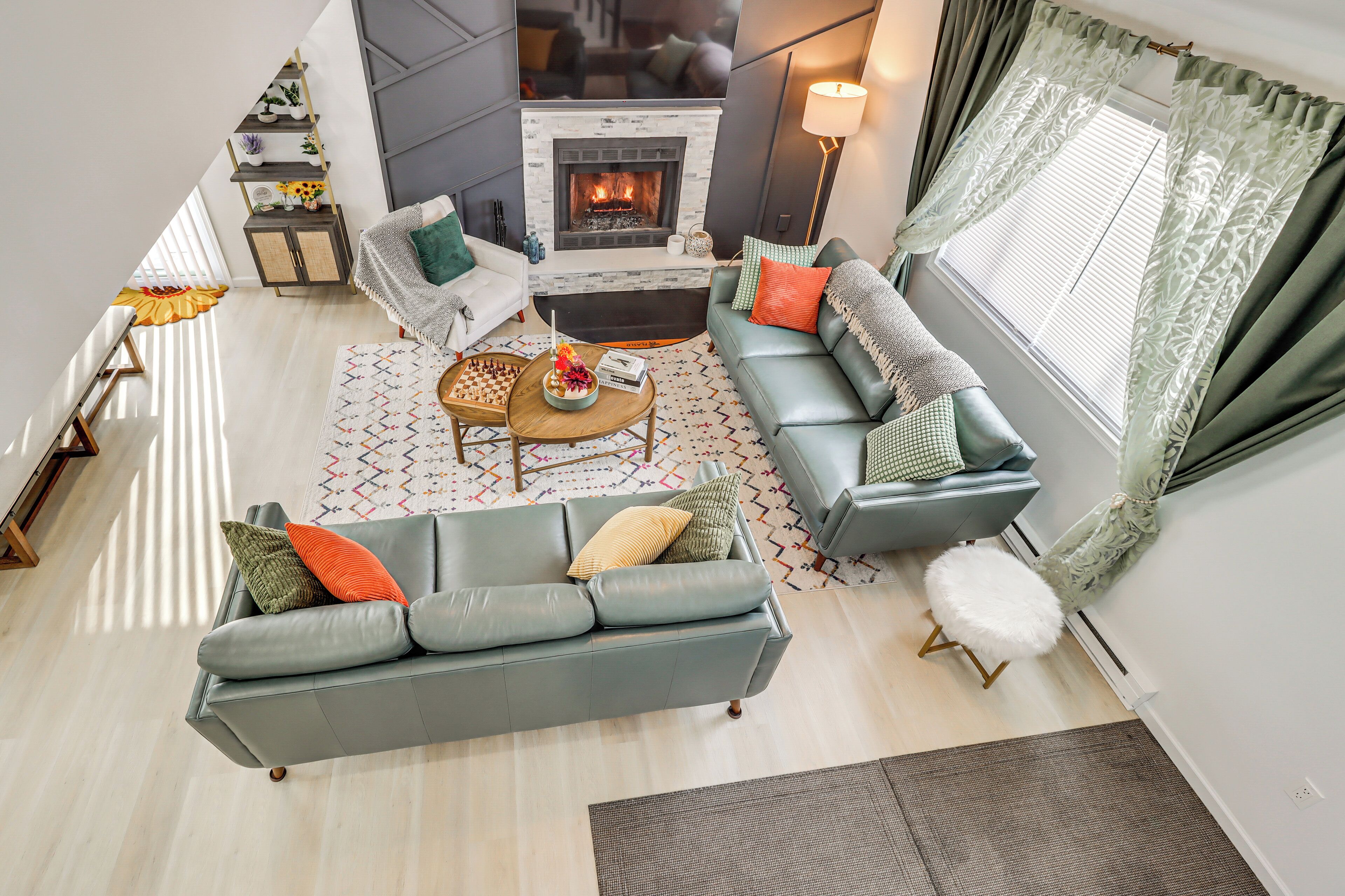 A modern living room with a fireplace, grey sofas, a coffee table, and a patterned rug.