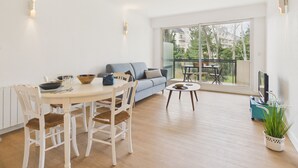 Una sala de estar moderna con una mesa de comedor, sillas, un sofá y un balcón con vista a la ciudad.