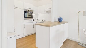 Una cocina moderna con armarios blancos, horno empotrado y encimera de madera.