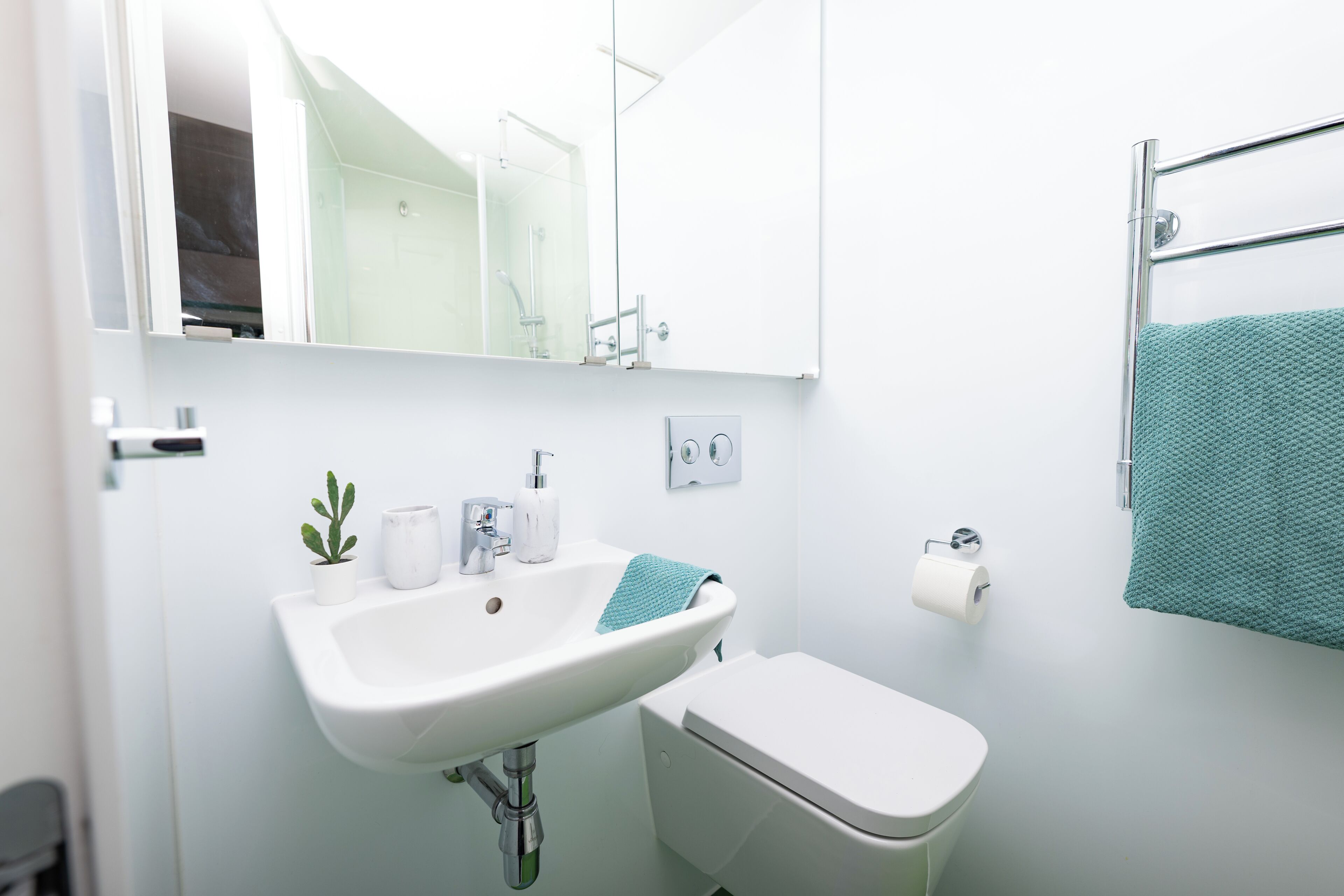 A bathroom with a white sink, toilet, and a towel rack with a towel.