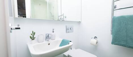 A bathroom with a white sink, toilet, and a towel rack with a towel.