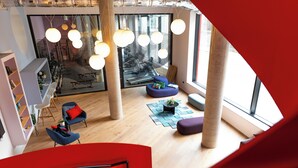 Ein modernes Interieur mit Treppe, Sitzbereichen und großen Fenstern.