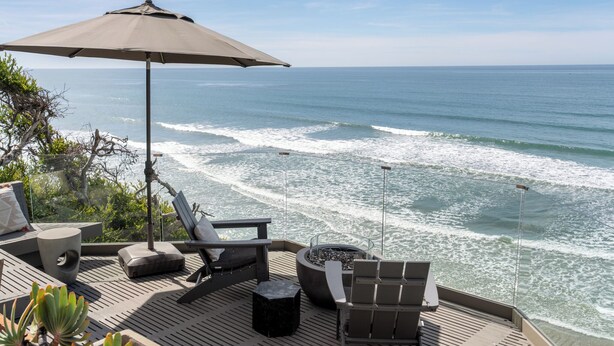 A deck with outdoor seating, a fire pit, and a view of the ocean. - Private Bluff-Top Oceanfront Estate | Beach Access (Encinitas)