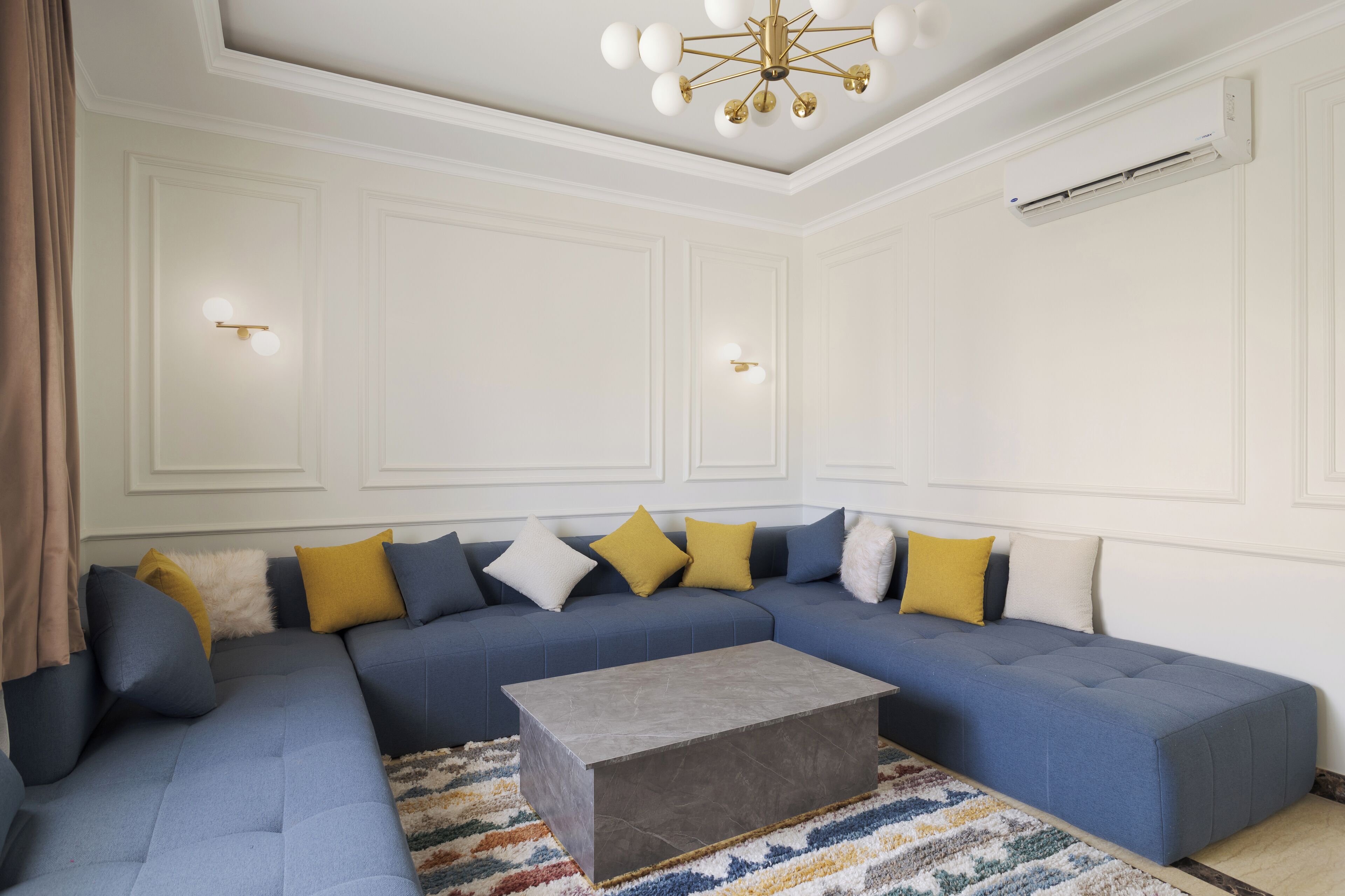 Uma sala de estar com sofá seccional, mesa de centro e luminária de teto.