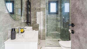 A modern bathroom with a glass-enclosed shower, a white sink, and a large mirror. - Casino & Mall Luxury Penthouse Suite (Limassol)