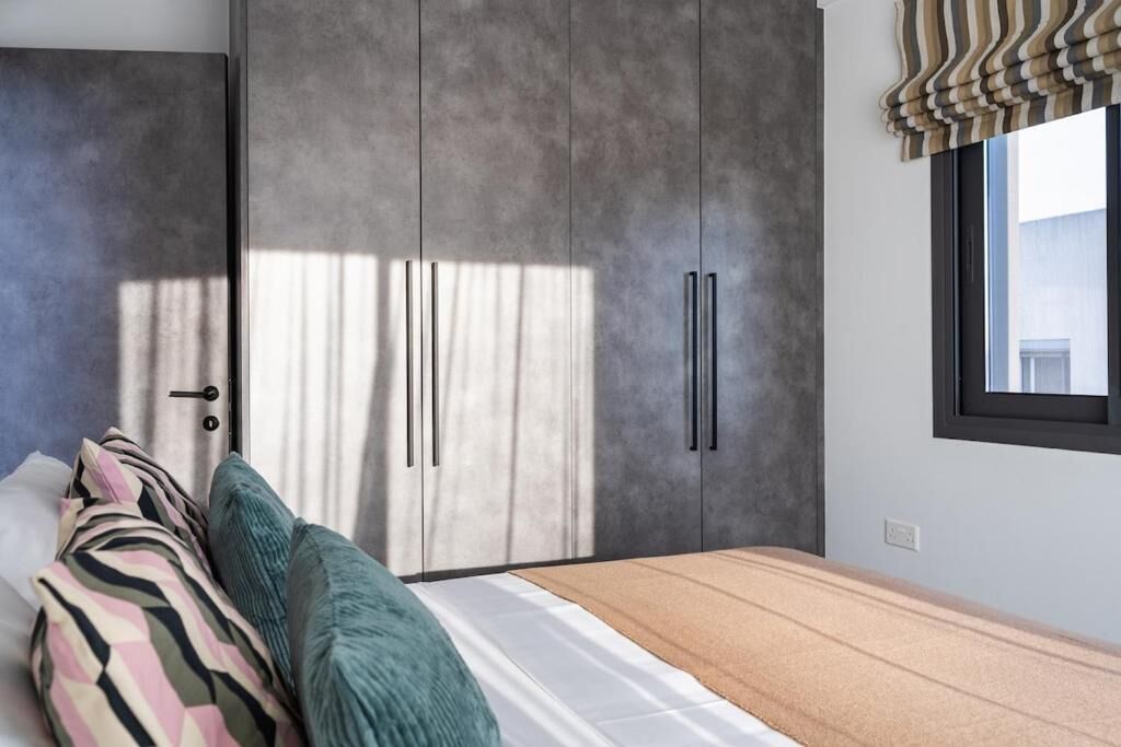 Un dormitorio con cama, almohadas, un armario y una ventana.