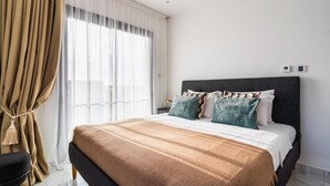 A modern hotel room with a large bed, beige curtains, and a view of the city. - Casino & Mall Luxury Penthouse Suite (Limassol)
