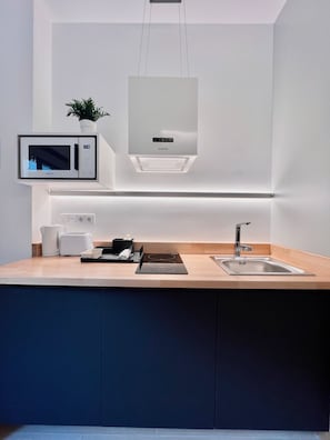 A modern kitchen with a built-in microwave, a kettle, a toaster, and a sink. - Sorolla Urban Suites (Valencia)