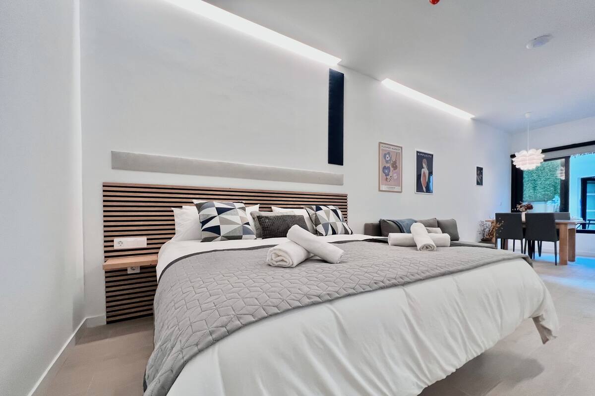 A modern bedroom with a large bed, a desk, and a chair.