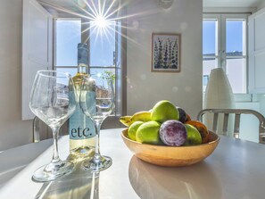 Et bord med en vinflaske, to vinglas og en skål med frugt.